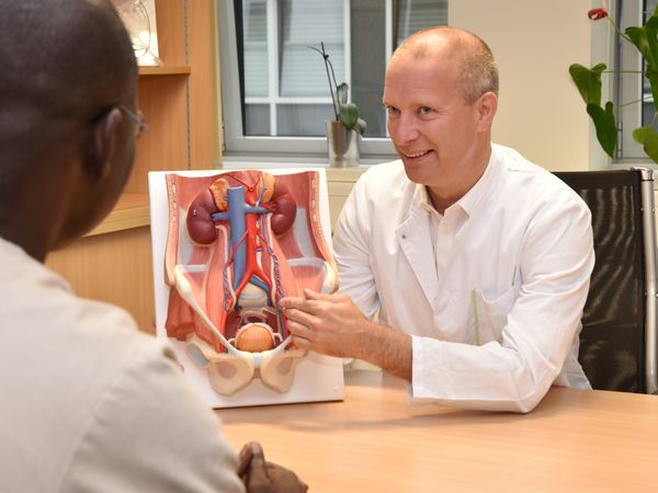 Arzt erläutert anhand eines Unterleibsmodells den geplanten Eingriff.