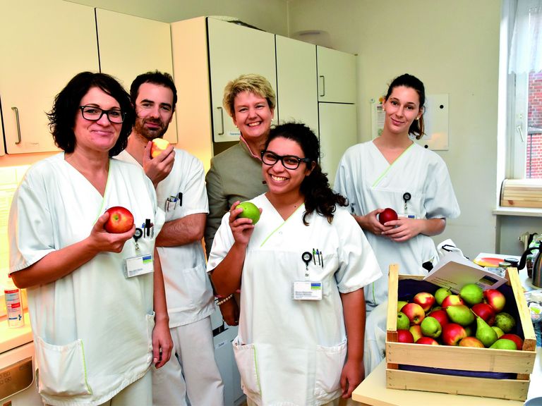 Pflegekräfte freuen sich über frische Äpfel und Birnen.
