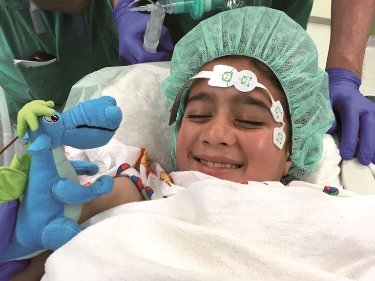 Kleines Mädchen lässt sich vor ihrer Herzoperation mit einem Plüschdrachen aufmuntern.