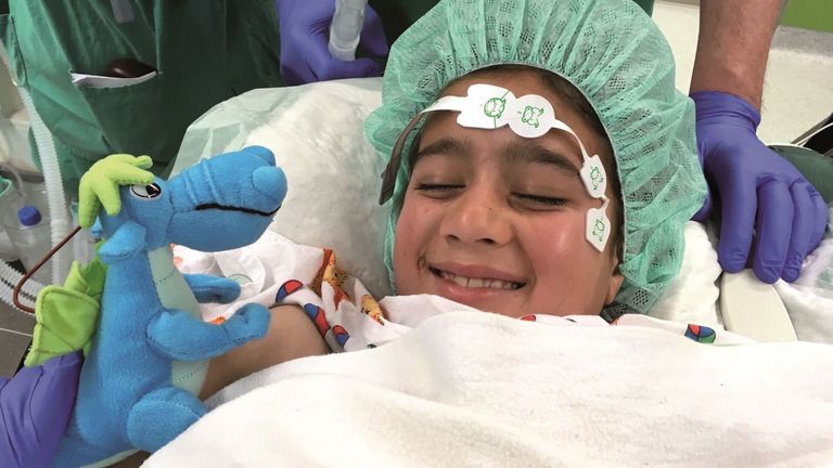 Kleines Mädchen lässt sich vor ihrer Herzoperation mit einem Plüschdrachen aufmuntern.