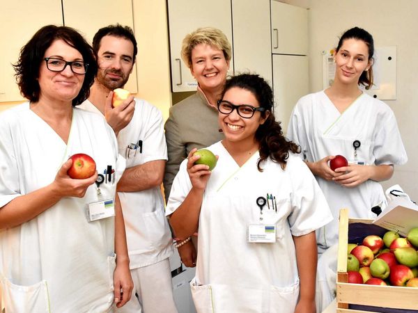 Pflegekräfte freuen sich über frische Äpfel und Birnen.