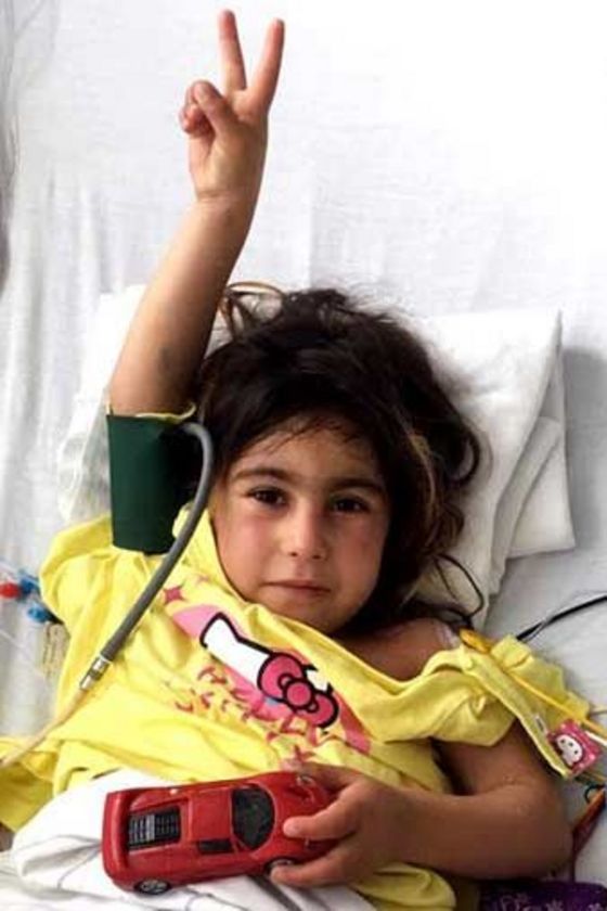 Mädchen zeigt im Krankenbett das Victory-Zeichen nach erfolgreicher Operation..